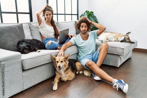 Photography Young hispanic couple with dogs relaxing at home confuse and wondering about question