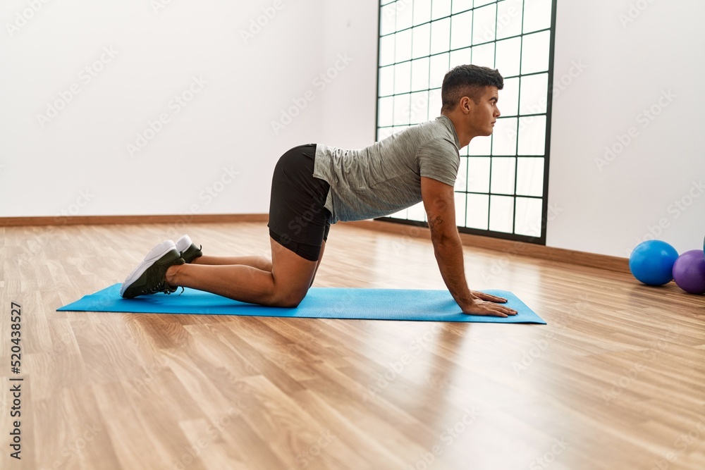 Young hispanic man stretching at sport center