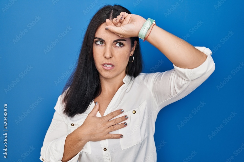 Young hispanic woman standing over blue background touching forehead for illness and fever, flu and cold, virus sick Young hispanic woman standing over blue background touching forehead for illness and fever, flu and cold, virus sick