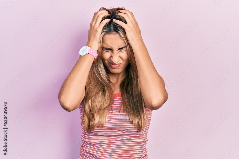Beautiful hispanic woman wearing casual summer t shirt suffering from headache desperate and stressed because pain and migraine. hands on head. Beautiful hispanic woman wearing casual summer t shirt suffering from headache desperate and stressed because pain and migraine. hands on head.
