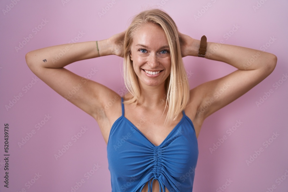 Young caucasian woman standing over pink background relaxing and stretching, arms and hands behind head and neck smiling happy Young caucasian woman standing over pink background relaxing and stretching, arms and hands behind head and neck smiling happy
