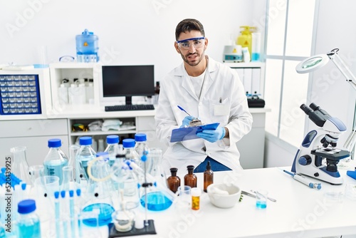 Handsome hispanic man working as scientific at laboratory