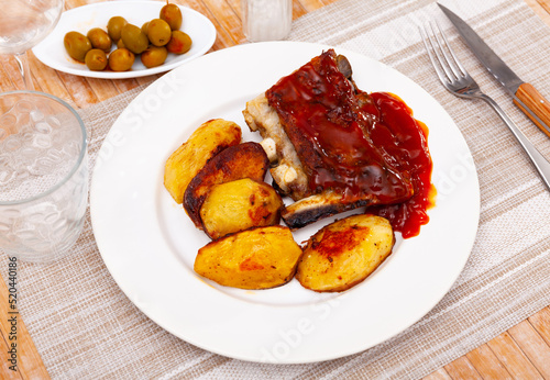 Tasty pork ribs baked under sauce, served with potatoes