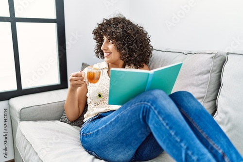 Young middle east woman drinking tea reading book at home photo