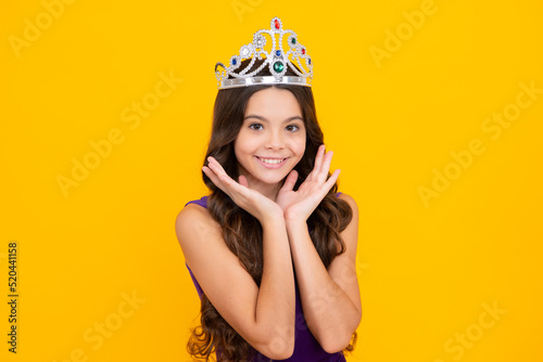 Little queen wearing golden crown. Teenage girl princess holding crown tiara. Prom party, childhood concept. Happy girl face, positive and smiling emotions. © Olena