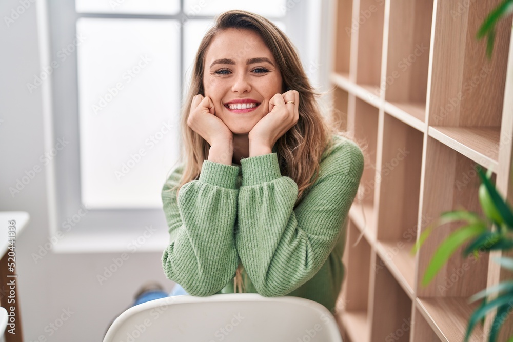 Young woman smiling confident sitting on chair at home