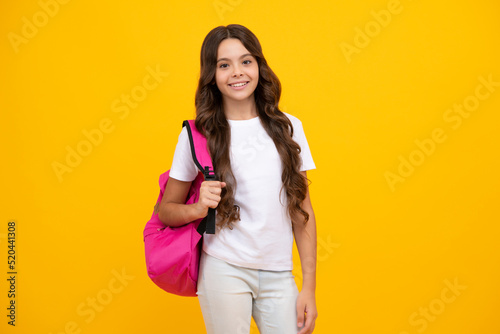 Schoolgirl in school uniform with school bag. Schoolchild, teen student hold backpack on yellow isolated background.