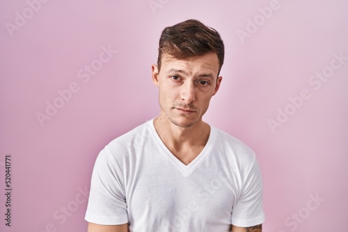 Caucasian man standing over pink background looking sleepy and tired, exhausted for fatigue and hangover, lazy eyes in the morning.