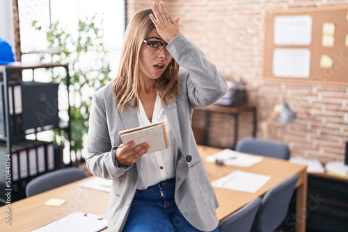 Young hispanic woman working at the office wearing glasses surprised with hand on head for mistake, remember error. forgot, bad memory concept. © Krakenimages.com