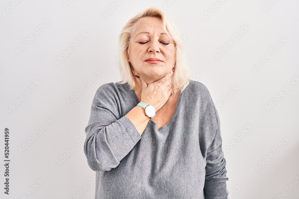 Middle age caucasian woman standing over white background touching painful neck, sore throat for flu, clod and infection Middle age caucasian woman standing over white background touching painful neck, sore throat for flu, clod and infection