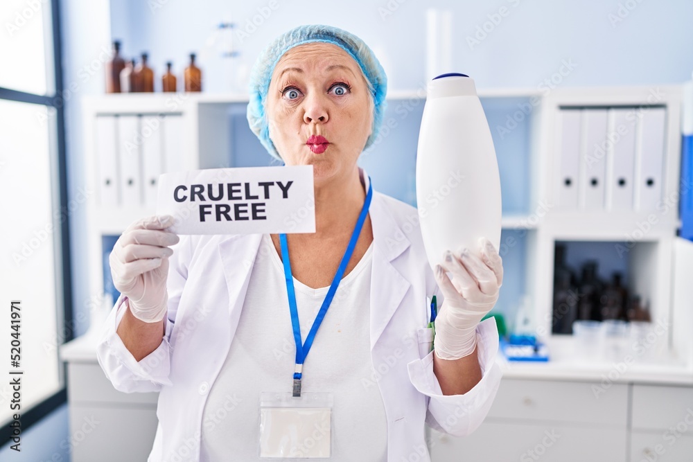 Middle age caucasian woman working on cruelty free laboratory making fish face with mouth and squinting eyes, crazy and comical. Middle age caucasian woman working on cruelty free laboratory making fish face with mouth and squinting eyes, crazy and comical.