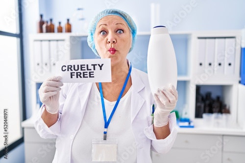 Middle age caucasian woman working on cruelty free laboratory making fish face with mouth and squinting eyes, crazy and comical.