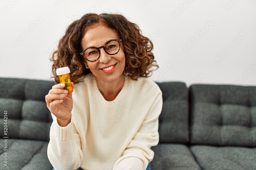 Middle age hispanic woman smiling confident holding pills at home Middle age hispanic woman smiling confident holding pills at home