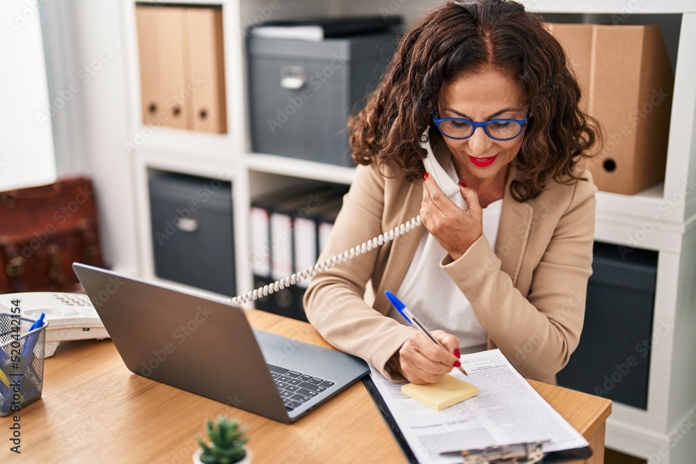 Middle age hispanic woman working with laptop at the office Middle age hispanic woman working with laptop at the office