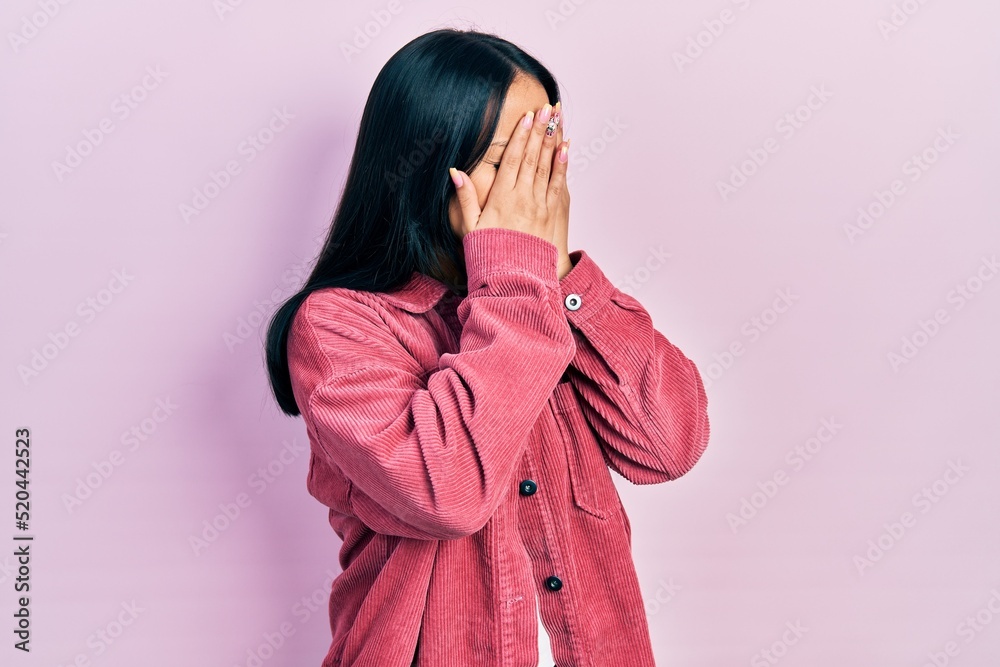 Beautiful hispanic woman with nose piercing wearing casual pink jacket with sad expression covering face with hands while crying. depression concept. Beautiful hispanic woman with nose piercing wearing casual pink jacket with sad expression covering face with hands while crying. depression concept.