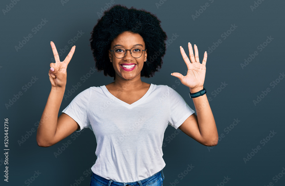 Young african american woman wearing casual white t shirt showing and pointing up with fingers number seven while smiling confident and happy. Young african american woman wearing casual white t shirt showing and pointing up with fingers number seven while smiling confident and happy.