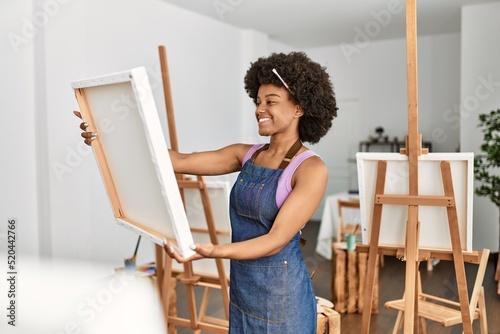 Young african american woman smiling confident holding canvas draw at art studio