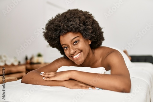 Young african american woman smiling confident lying on massage table at beauty center