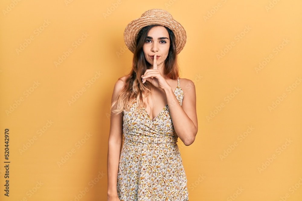 Young hispanic girl wearing summer hat asking to be quiet with finger on lips. silence and secret concept. Young hispanic girl wearing summer hat asking to be quiet with finger on lips. silence and secret concept.