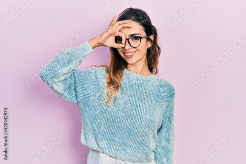 Young hispanic girl wearing casual clothes and glasses smiling happy doing ok sign with hand on eye looking through fingers © Krakenimages.com