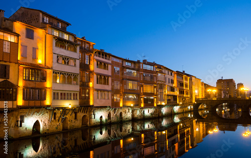 View of lighted Agout river with fringing with old houses and bridges in French town of Castres at dusk photo