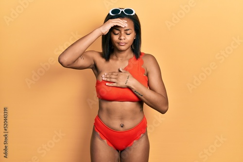 Young african american girl wearing bikini touching forehead for illness and fever, flu and cold, virus sick