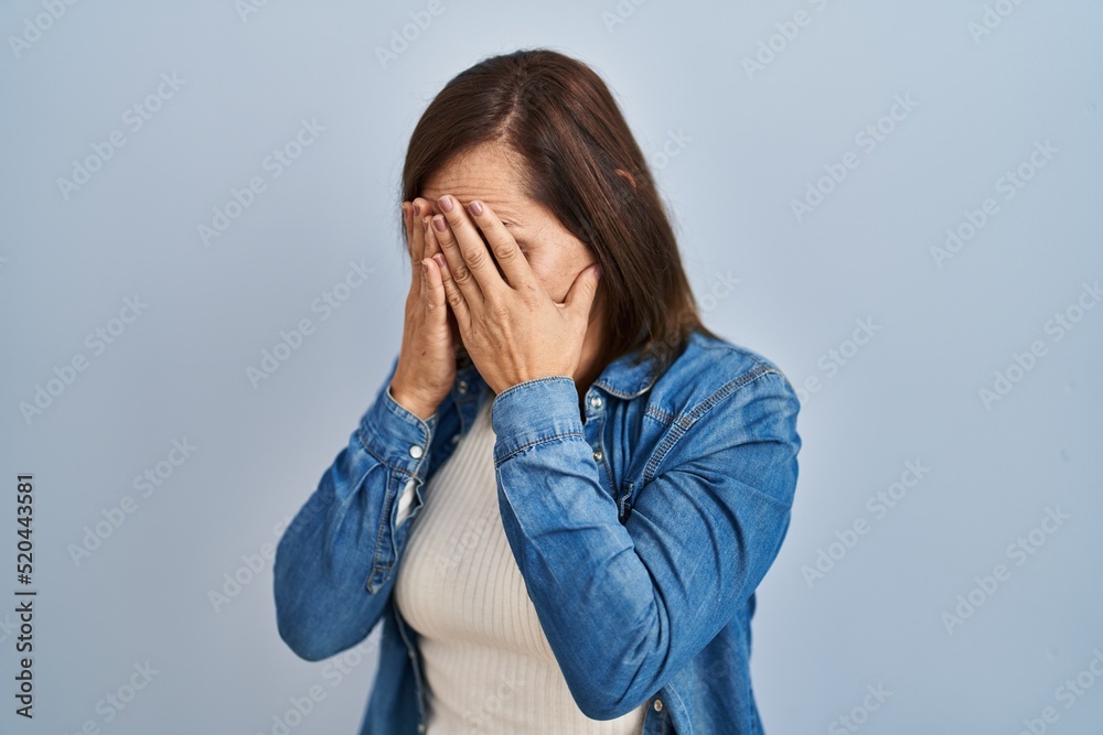 Middle age brunette woman wearing casual denim jacket over isolated background with sad expression covering face with hands while crying. depression concept. Middle age brunette woman wearing casual denim jacket over isolated background with sad expression covering face with hands while crying. depression concept.