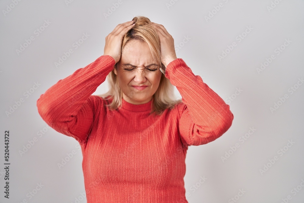 Blonde woman standing over isolated background suffering from headache desperate and stressed because pain and migraine. hands on head. Blonde woman standing over isolated background suffering from headache desperate and stressed because pain and migraine. hands on head.