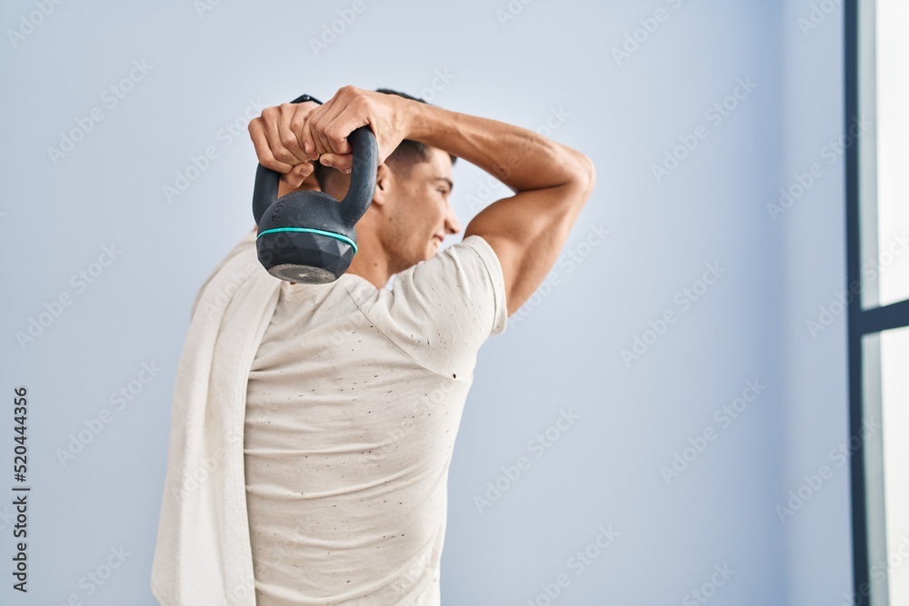 Young hispanic man smiling confident training using kettlebell at sport center Young hispanic man smiling confident training using kettlebell at sport center