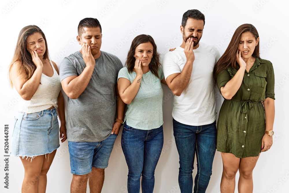 Group of young hispanic friends standing together over isolated background touching mouth with hand with painful expression because of toothache or dental illness on teeth. dentist concept. Group of young hispanic friends standing together over isolated background touching mouth with hand with painful expression because of toothache or dental illness on teeth. dentist concept.