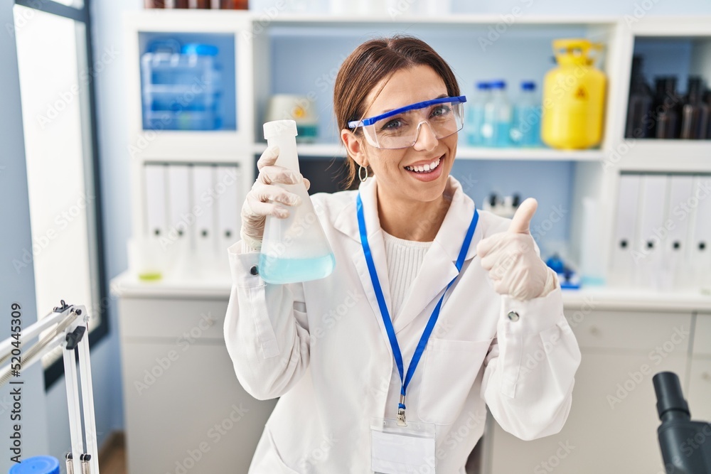 Young brunette woman working at scientist laboratory smiling happy and positive, thumb up doing excellent and approval sign Young brunette woman working at scientist laboratory smiling happy and positive, thumb up doing excellent and approval sign