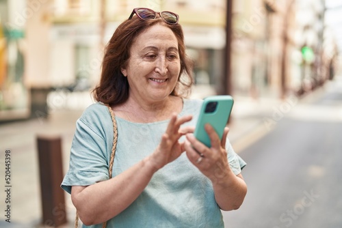 Senior woman smiling confident using smartphone at street