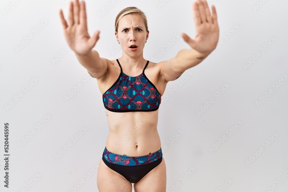 Young blonde woman wearing sporty bikini over isolated background doing stop gesture with hands palms, angry and frustration expression Young blonde woman wearing sporty bikini over isolated background doing stop gesture with hands palms, angry and frustration expression