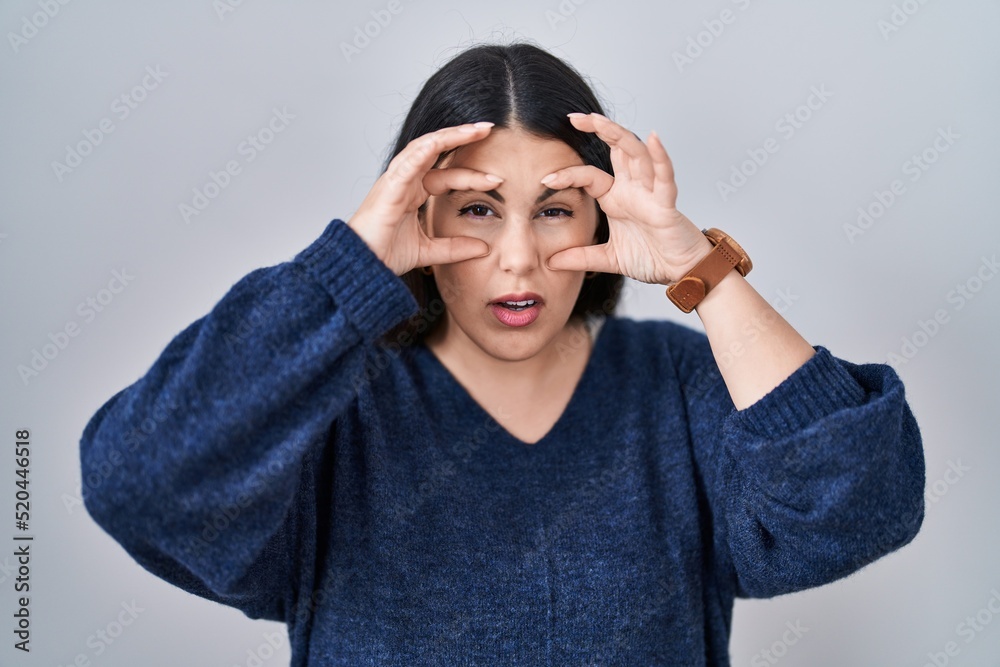 Young brunette woman standing over isolated background trying to open eyes with fingers, sleepy and tired for morning fatigue Young brunette woman standing over isolated background trying to open eyes with fingers, sleepy and tired for morning fatigue