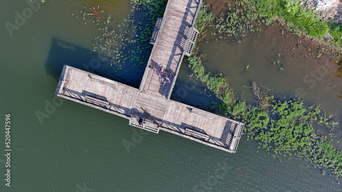 Aerial overhead view of people with bicycles on fishing pier at lake
