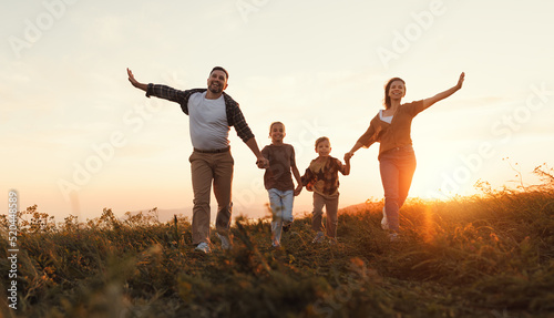 Happy family: mother, father, children son and daughter running on sunset