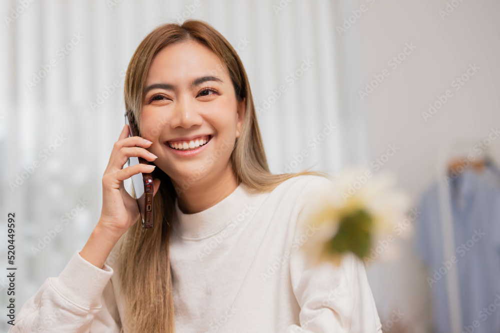 Phone conversation. Confident Asian woman sit on couch talk speak communicate by telephone from home holding device at ear. Phone conversation. Confident Asian woman sit on couch talk speak communicate by telephone from home holding device at ear.