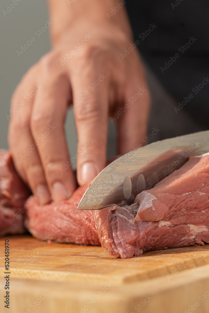 Vertical photo with close up view of a chef slicing meat into pieces
