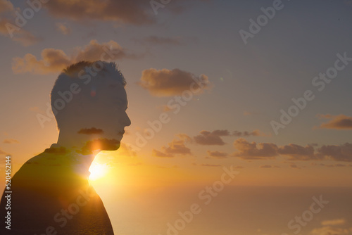 silhouette of young man standing facing the sunrise 