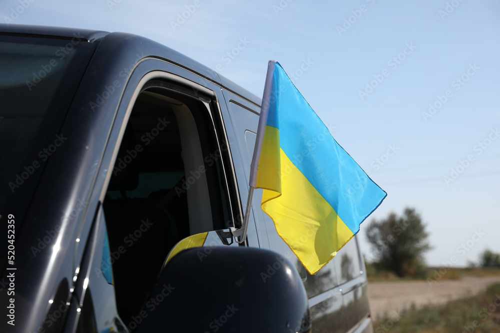Fototapeta premium National flag of Ukraine on car window outdoors, closeup