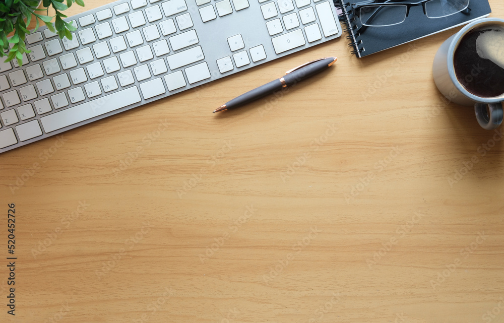 Top view wooden office desk with notepad, sticky note, eyeglasses, coffee cup and potted plant. Copy space for your text.
