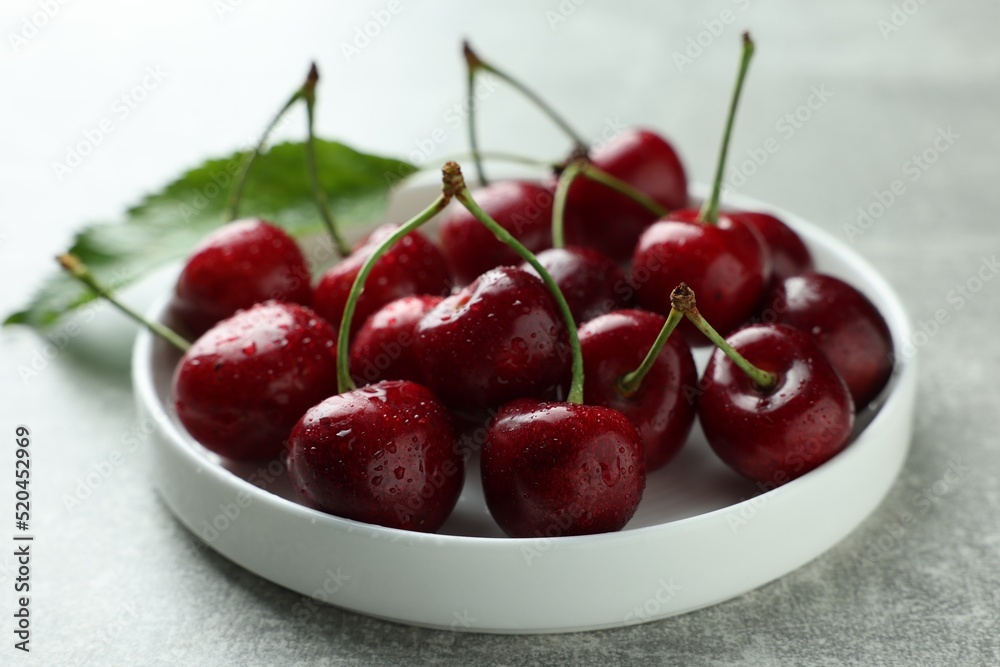 Fresh ripe cherries with water drops on light grey table, closeup Fresh ripe cherries with water drops on light grey table, closeup