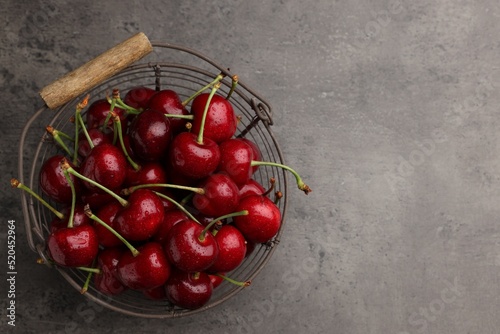 Metal basket with ripe sweet cherries on grey table, top view. Space for text