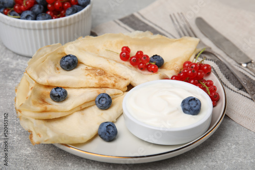 Delicious crepes with natural yogurt, blueberries and red currants on grey table