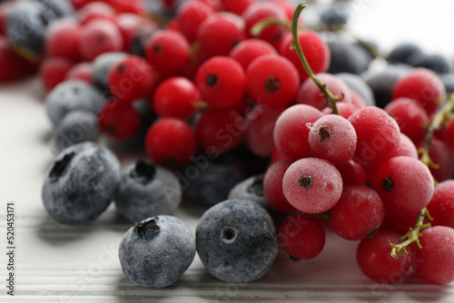 Принти на полотні Tasty frozen blueberries and red currants on white wooden table, closeup