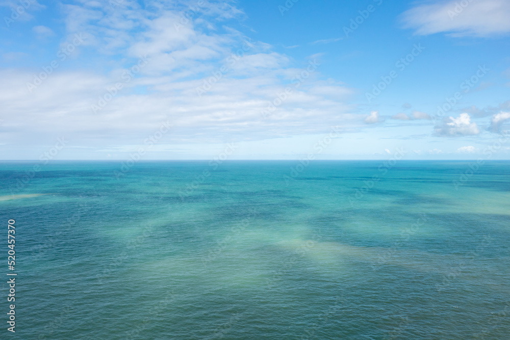 vista aérea das águas claras do Mar da Bahia com céu azul e algumas nuvens 