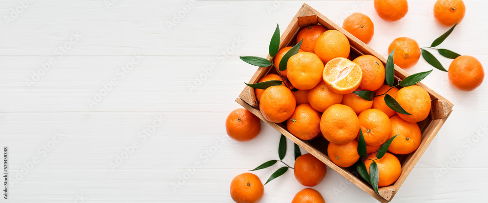 Box of sweet tangerines on white wooden background with space for text