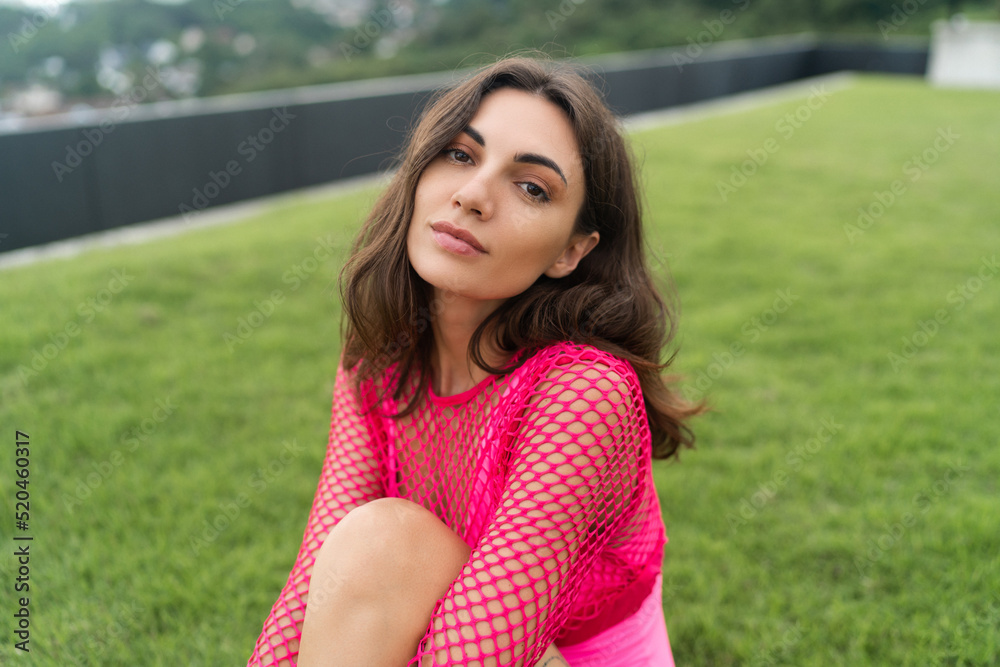 A slender young woman in a bright swimsuit on the grass by the pool. Slim athletic girl posing, tender romantic, looking at the camera A slender young woman in a bright swimsuit on the grass by the pool. Slim athletic girl posing, tender romantic, looking at the camera