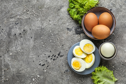 Composition with boiled chicken eggs and lettuce on grunge background