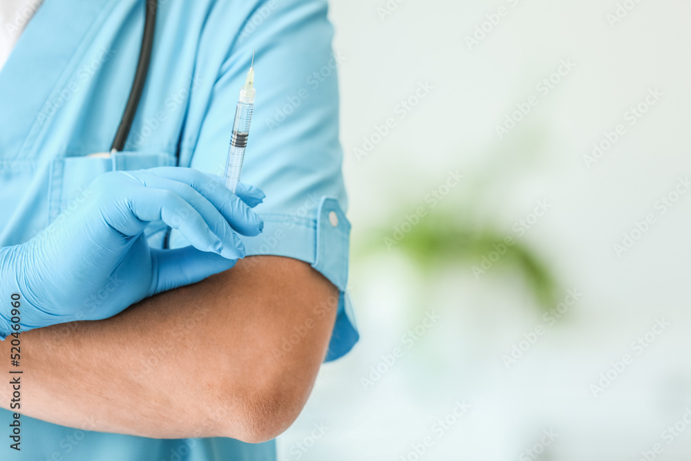 Male doctor with syringe in clinic, closeup